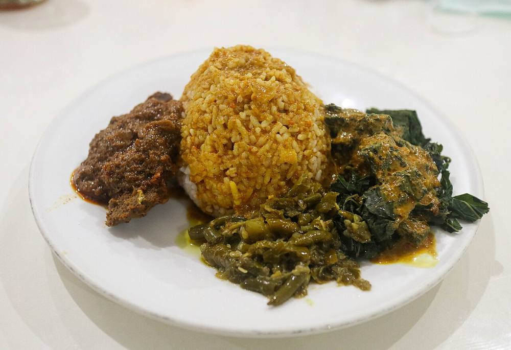 A plate of nasi Padang: white rice with beef rendang, cassava leaves and green chilli sambal
